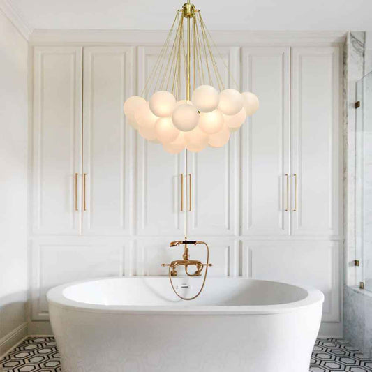 Lustre à boules en verre blanc suspendu au-dessus d’une baignoire, monture dorée.