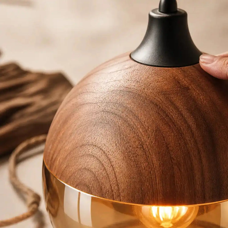 Dôme en bois clair à veinures, main près du verre, ampoule visible