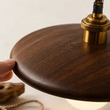 Abat-jour en bois brun texturé, main au bord; ampoule ronde et douille laiton