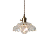 Suspension en verre transparent style lotus avec ampoule visible, monture laiton.