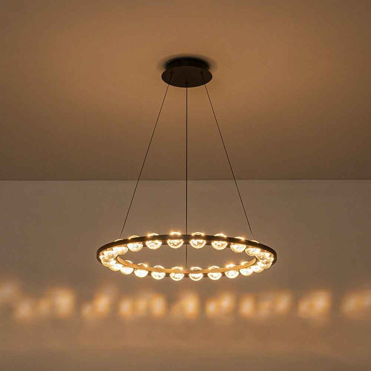 Lustre LED cercle noir allumé, anneau en verre émettant une lumière chaude.