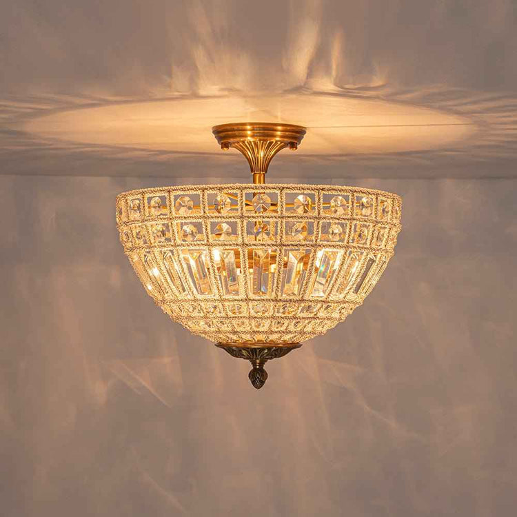 Plafonnier 3 lumières cristal et laiton, coupole ajourée diffusant une lumière chaude.