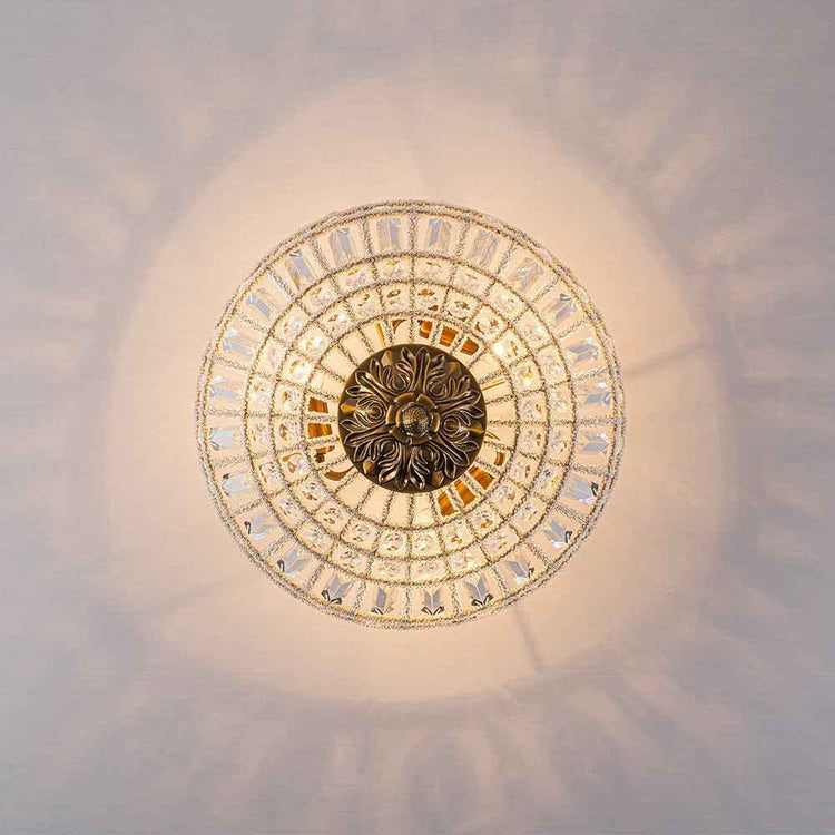 Plafonnier 3 lumières: rosace dorée au centre, couronne de cristal autour.