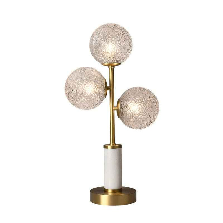 Lampe à poser 3 lumières : trois globes en verre texturé, tige laiton, base ronde dorée.