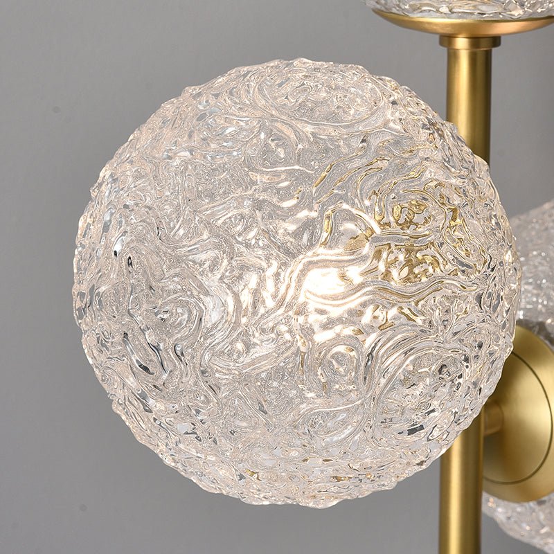 Globe en verre texturé d’une lampe à poser, monture laiton doré visible.