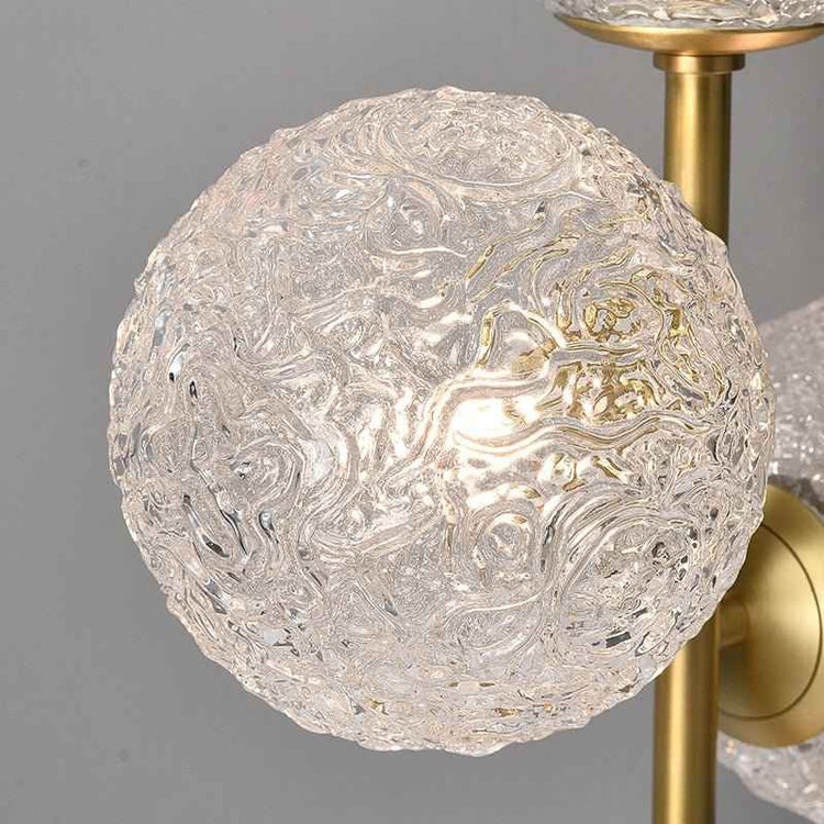 Globe en verre texturé d’une lampe à poser, monture laiton doré visible.