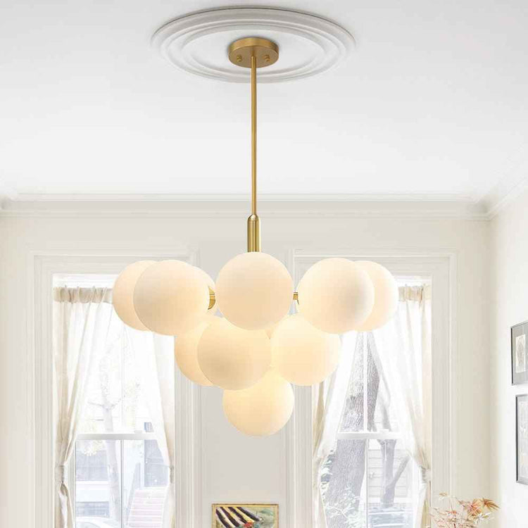 Lustre suspendu à plusieurs boules en verre opale laiteux, monture laiton au plafond.