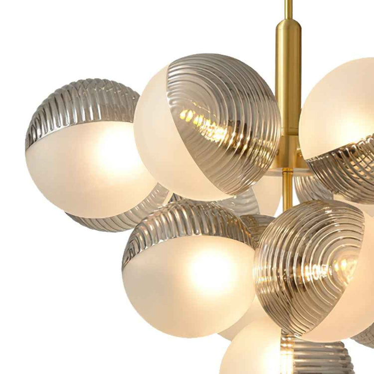 Gros plan sur boules de verre opale texturé, finitions gris, tige laiton du lustre.