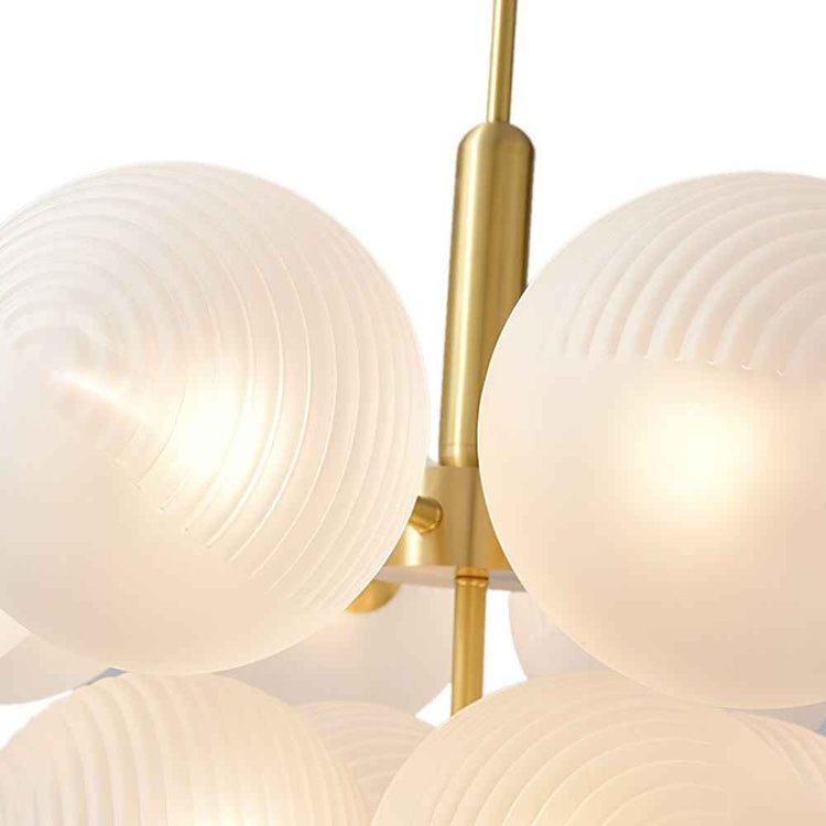 Boule en verre opale blanc texturé sur monture laiton, gros plan tiges et globes.