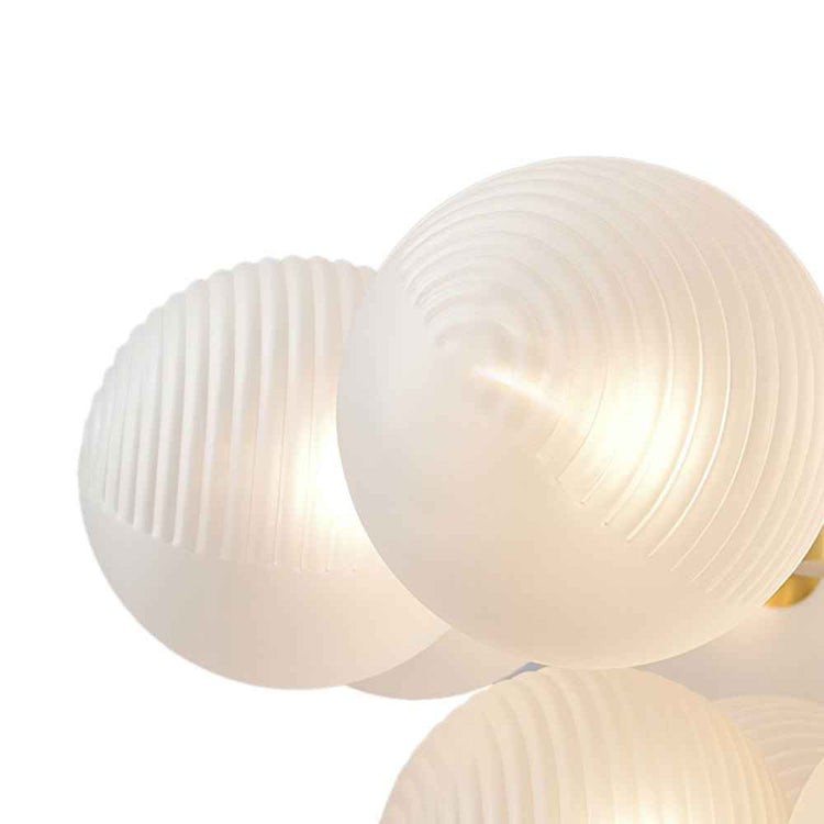 Boules en verre opale blanc texturé en grappe, monture laiton partiellement visible.