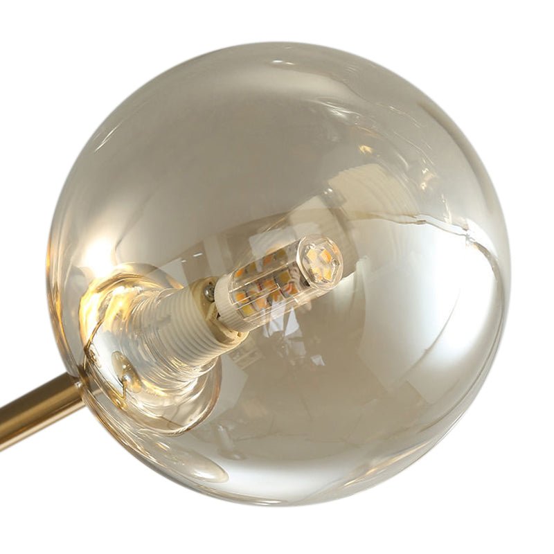 Globe en verre ambré du plafonnier, douille et ampoule visibles, monture dorée.