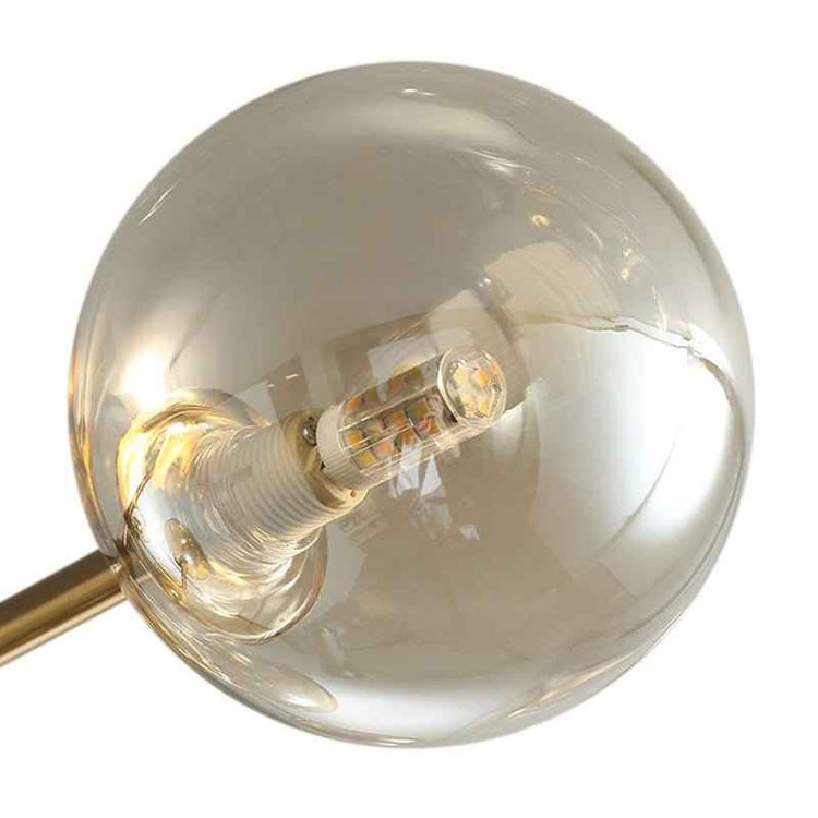 Globe en verre ambré du plafonnier, douille et ampoule visibles, monture dorée.
