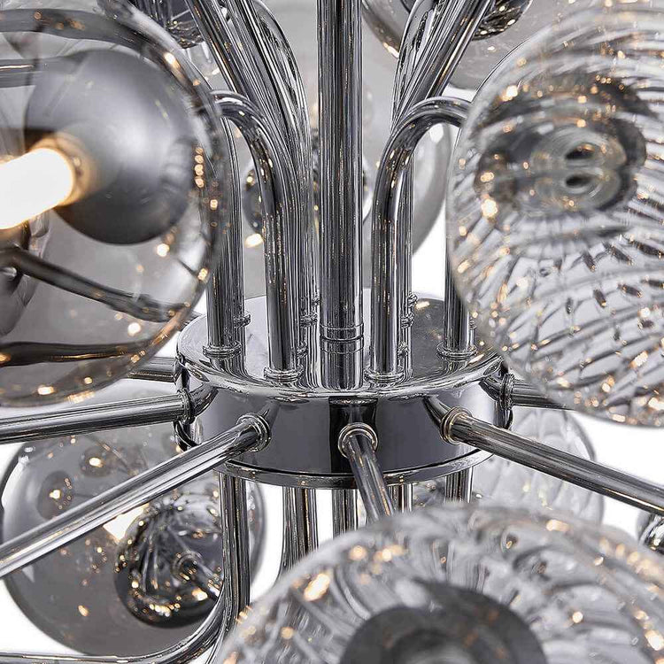Détail du lustre : nœud central chromé et bras métalliques entourés de boules de verre.