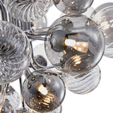 Détail du lustre : boules de verre fumé avec ampoules allumées et bras chromés.