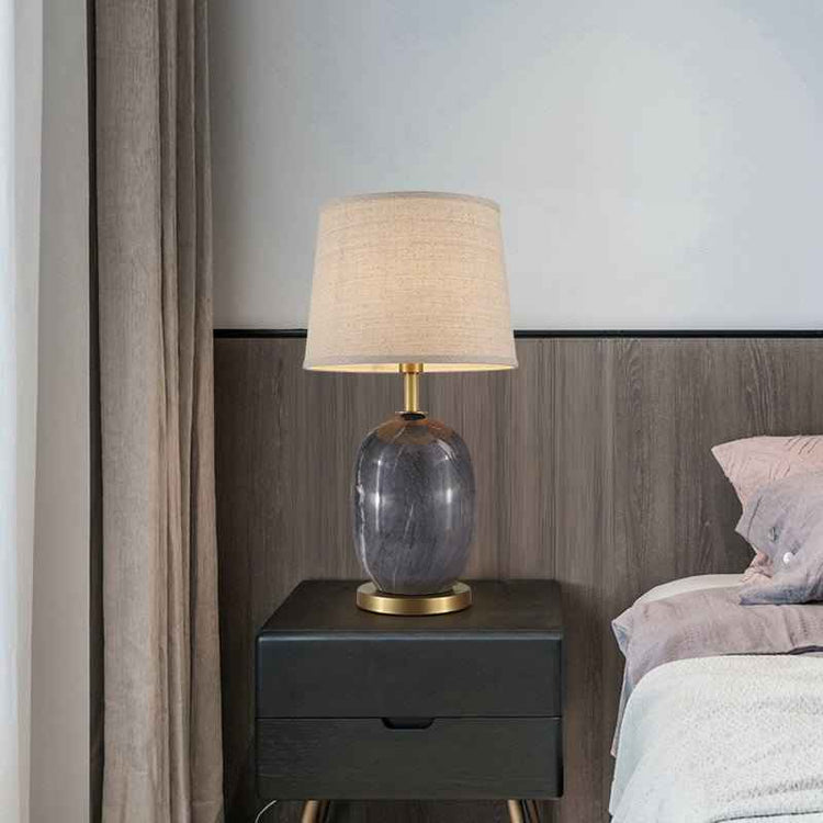 Lampe de table : abat-jour en tissu beige et base en céramique grise, finitions laiton