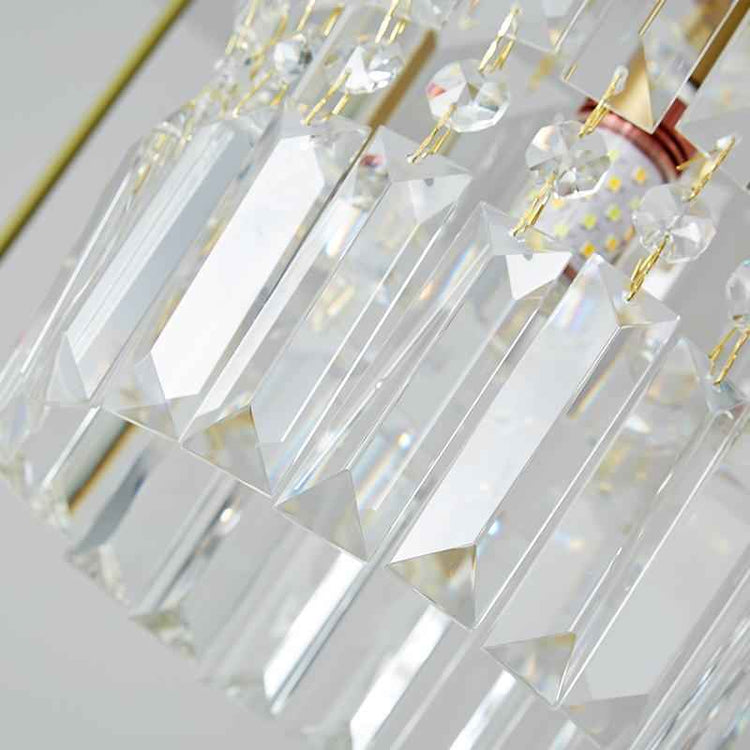 Gros plan sur prismes en cristal d’une suspension cylindrique, monture dorée