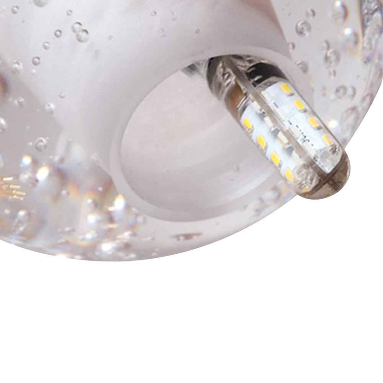 Globe en cristal avec ampoule LED visible, surface sphérique avec reflets et bulles.