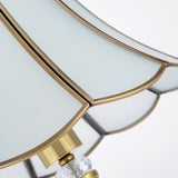 Base de lampe dorée avec élément central en cristal transparent et supports métalliques.