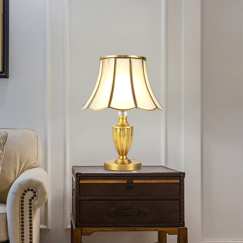 Lampe à poser dorée avec abat-jour octogonal à bords festonnés et pied conique.