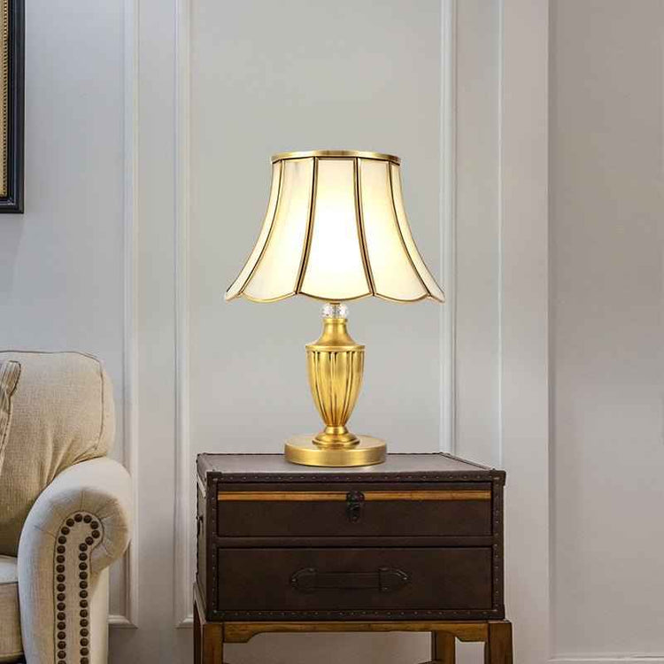 Lampe à poser dorée avec abat-jour octogonal à bords festonnés et pied conique.