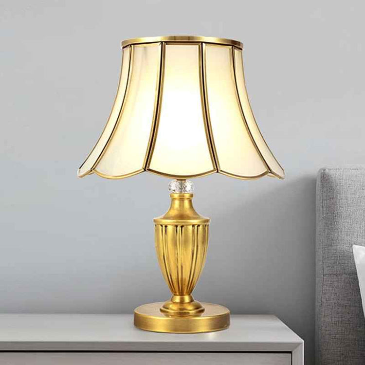Lampe à poser dorée : abat-jour octogonal à bords festonnés et pied en soucoupe.