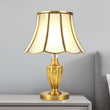 Lampe à poser dorée : abat-jour octogonal à bords festonnés et pied en soucoupe.