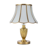 Lampe à poser dorée avec abat-jour évasé octogonal à bords festonnés.