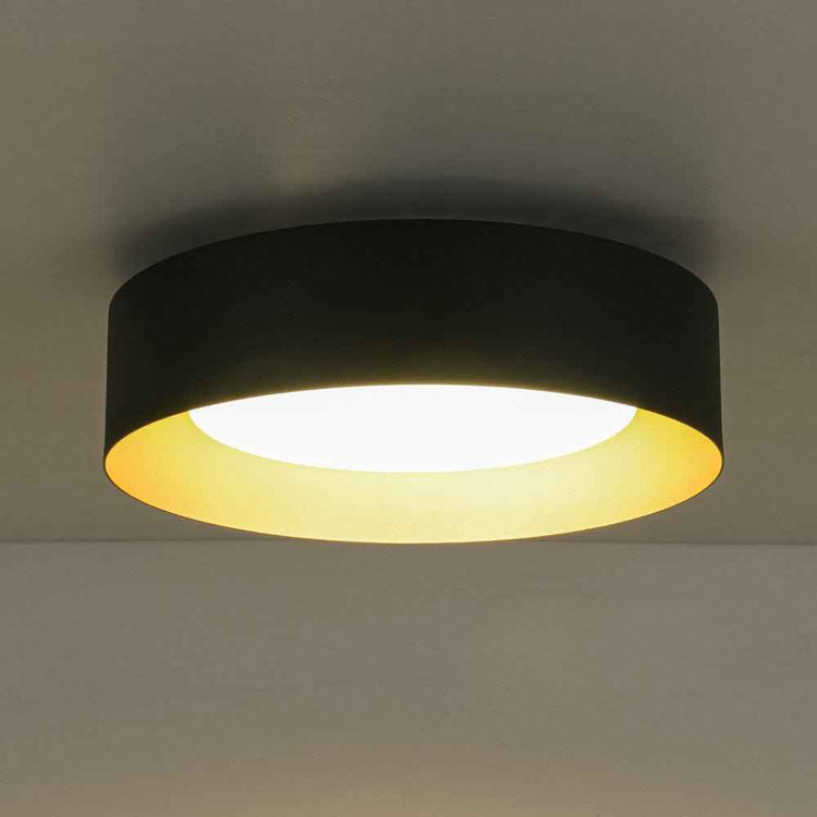 Plafonnier LED tambour noir, verre laiteux diffusant une lumière chaude.