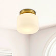 Plafonnier en verre cylindrique blanc, monture dorée au plafond