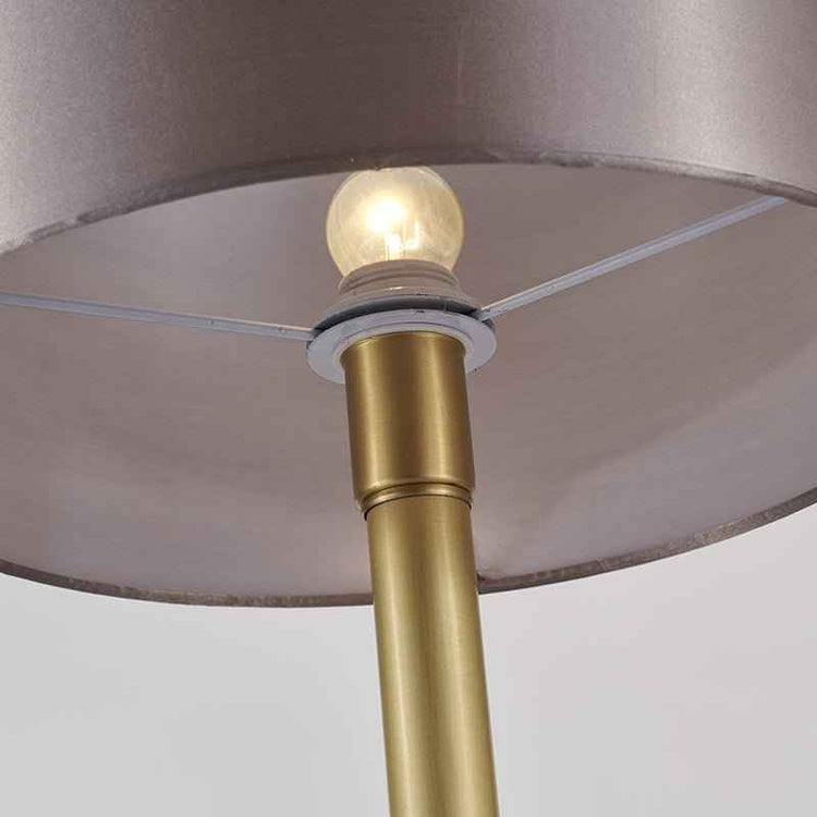 Lampe à poser avec ampoule allumée : abat-jour tissu beige rosé et pied doré à base marbre.