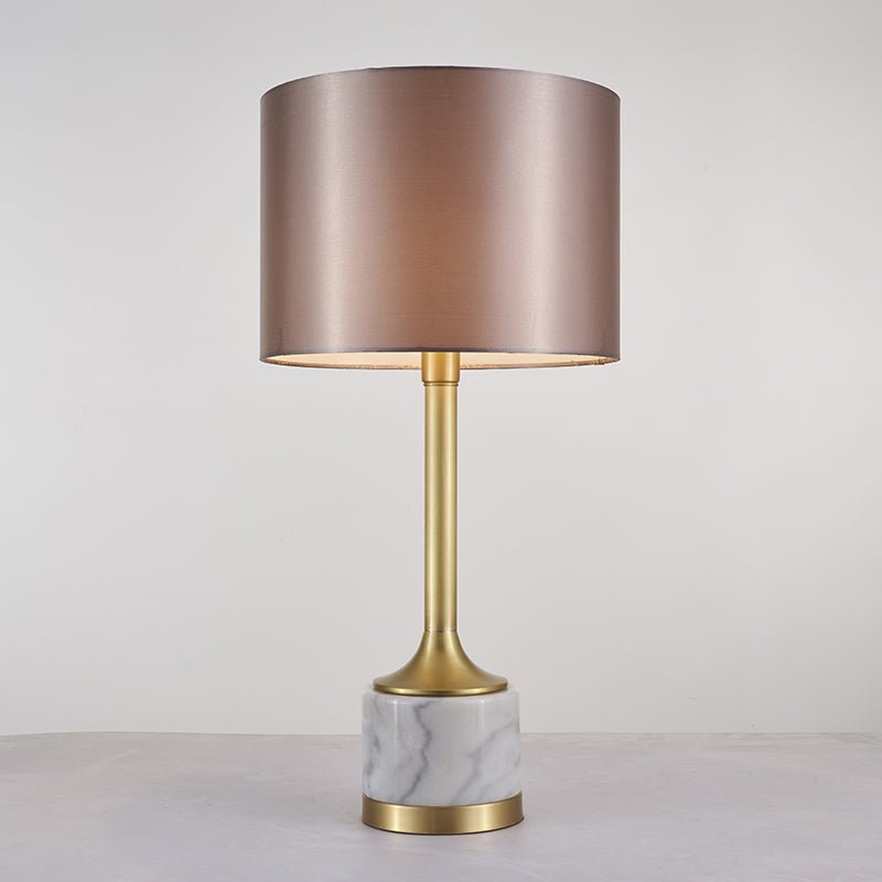 Lampe à poser : abat-jour tissu beige rosé, montant doré et base en marbre blanc veinuré.
