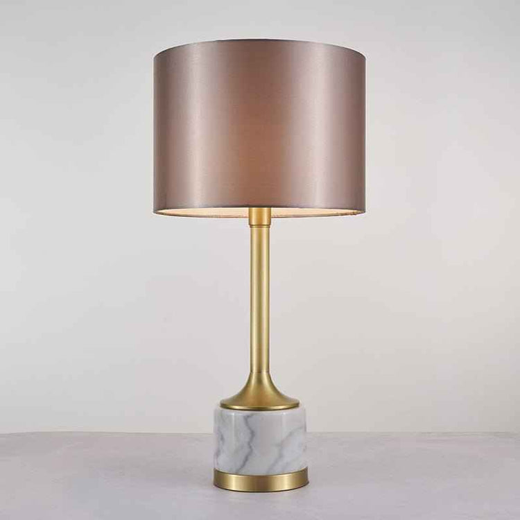 Lampe à poser : abat-jour tissu beige rosé, montant doré et base en marbre blanc veinuré.