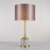Lampe à poser : abat-jour tissu beige rosé, montant doré et base en marbre blanc veinuré.