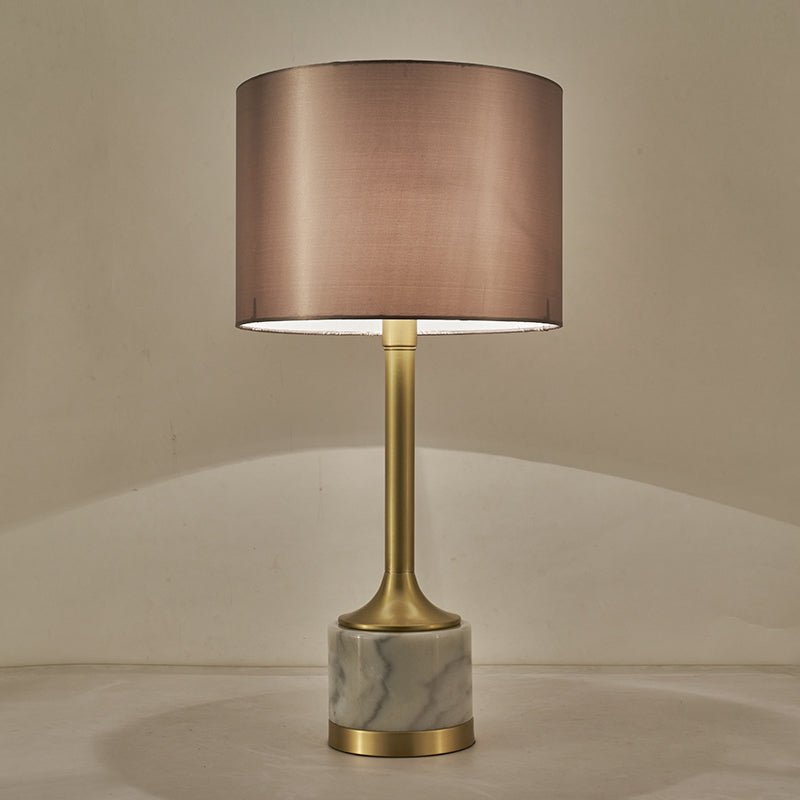 Lampe à poser à abat-jour en tissu beige rosé, pied doré et base en marbre blanc veinuré.