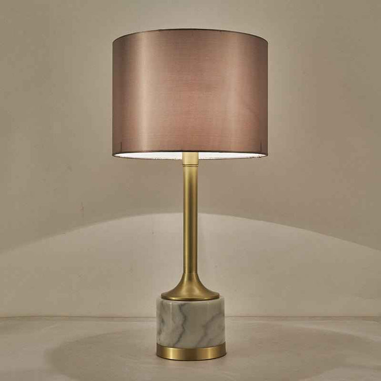 Lampe à poser à abat-jour en tissu beige rosé, pied doré et base en marbre blanc veinuré.