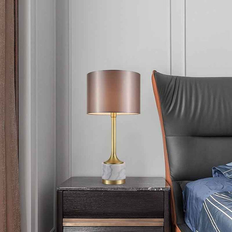 Lampe à poser avec abat-jour en tissu beige rosé et base en marbre blanc veinuré, finitions dorées.