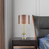 Lampe à poser avec abat-jour en tissu beige rosé et base en marbre blanc veinuré, finitions dorées.