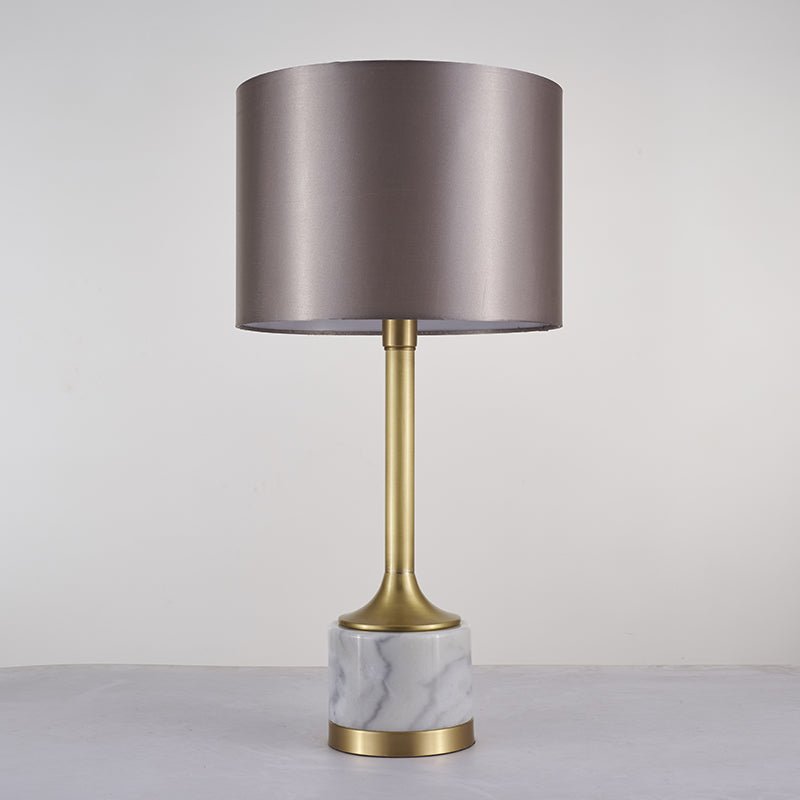 Lampe à poser avec abat-jour en tissu beige rosé et base en marbre blanc veinuré, détails dorés.