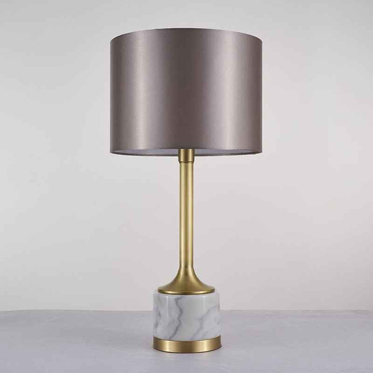 Lampe à poser avec abat-jour en tissu beige rosé et base en marbre blanc veinuré, détails dorés.
