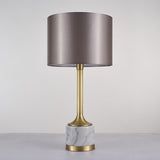 Lampe à poser avec abat-jour en tissu beige rosé et base en marbre blanc veinuré, détails dorés.