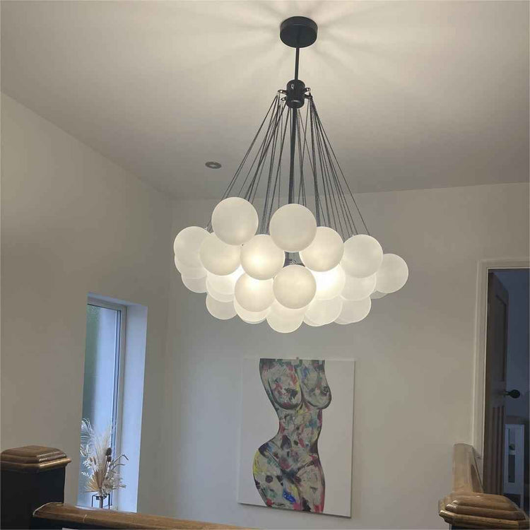 Lustre plafond moderne avec grappes de boules en verre blanc et tiges fines au centre.