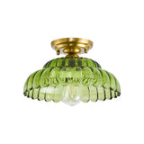 Plafonnier dôme en verre vert, forme bombée nervurée et base dorée.